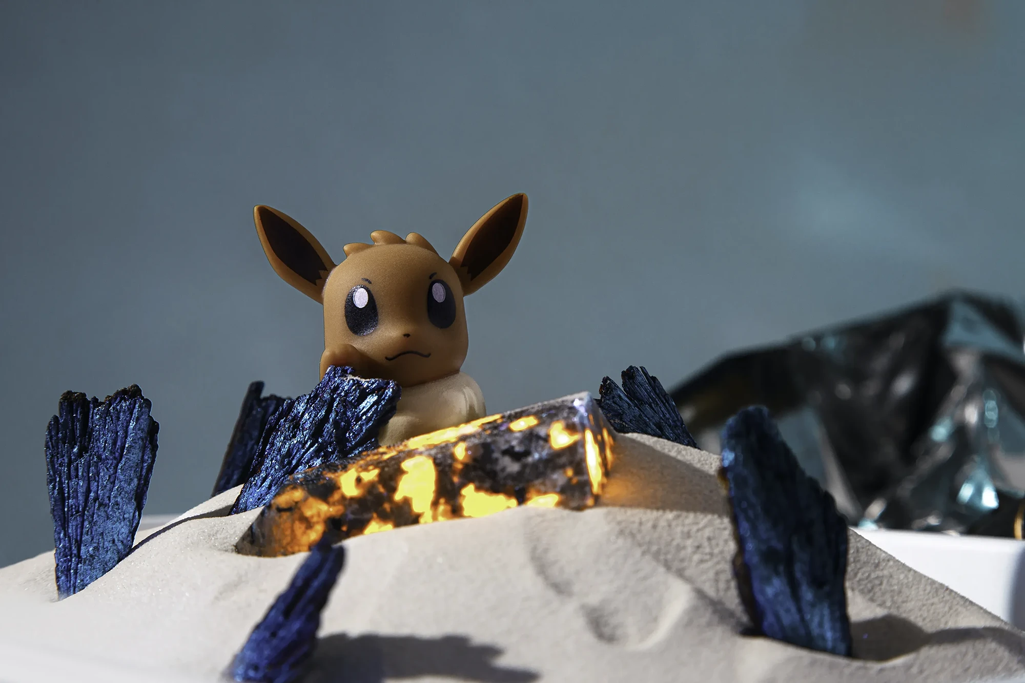 immagine stile pop di action figure Pokemon Eevee - immagine realizzata seguendo l'idea del personaggio e della sua personalità, integrando nell'immagine vari minerali e particolari si è riusciti a dare al personaggio vita e ambientarlo, il tutto realizzato in studio fotografico per aziende